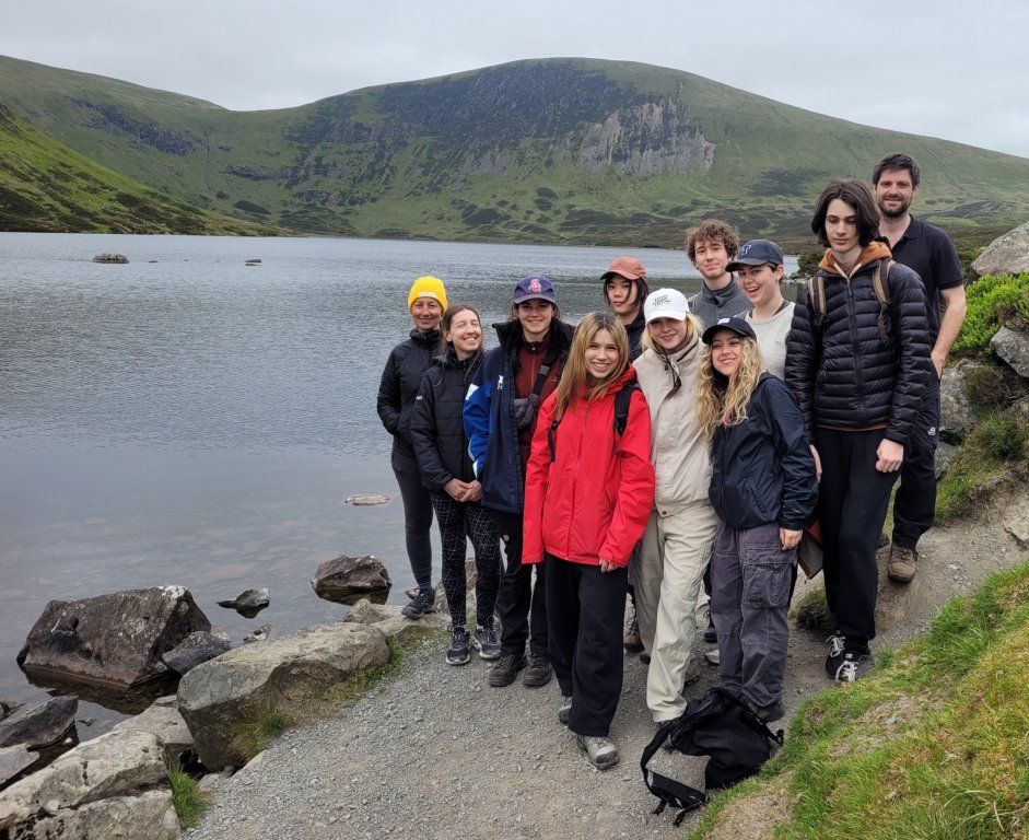 Group of students from Canada standing next to Loch Skene with hills in the background