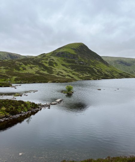 Group of students from Canada standing next to Loch Skene with hills in the background